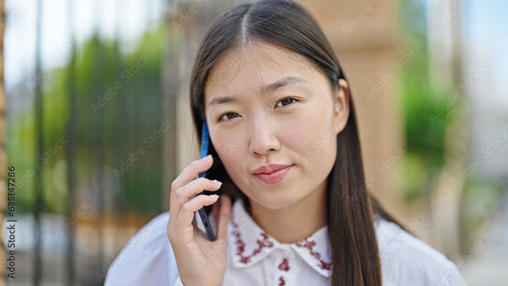 Young chinese woman talking on smartphone with serious expression at street Young chinese woman talking on smartphone with serious expression at street