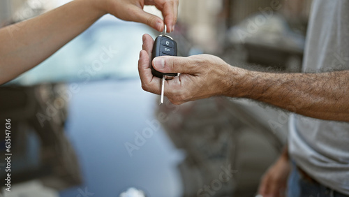 Young hispanic man receiving key of new car at street