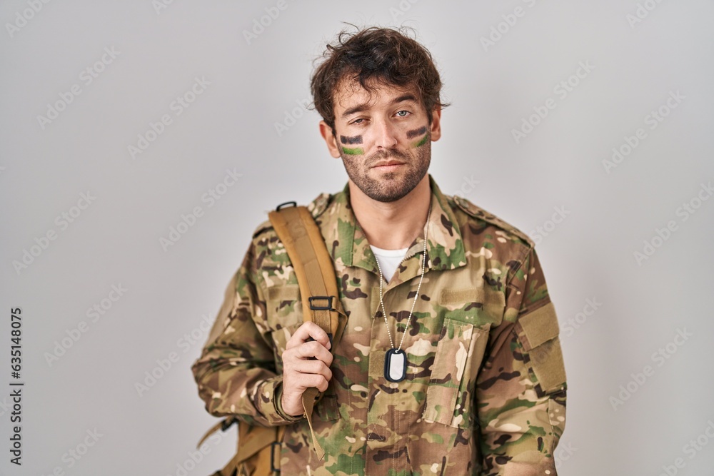 Hispanic young man wearing camouflage army uniform looking sleepy and tired, exhausted for fatigue and hangover, lazy eyes in the morning.