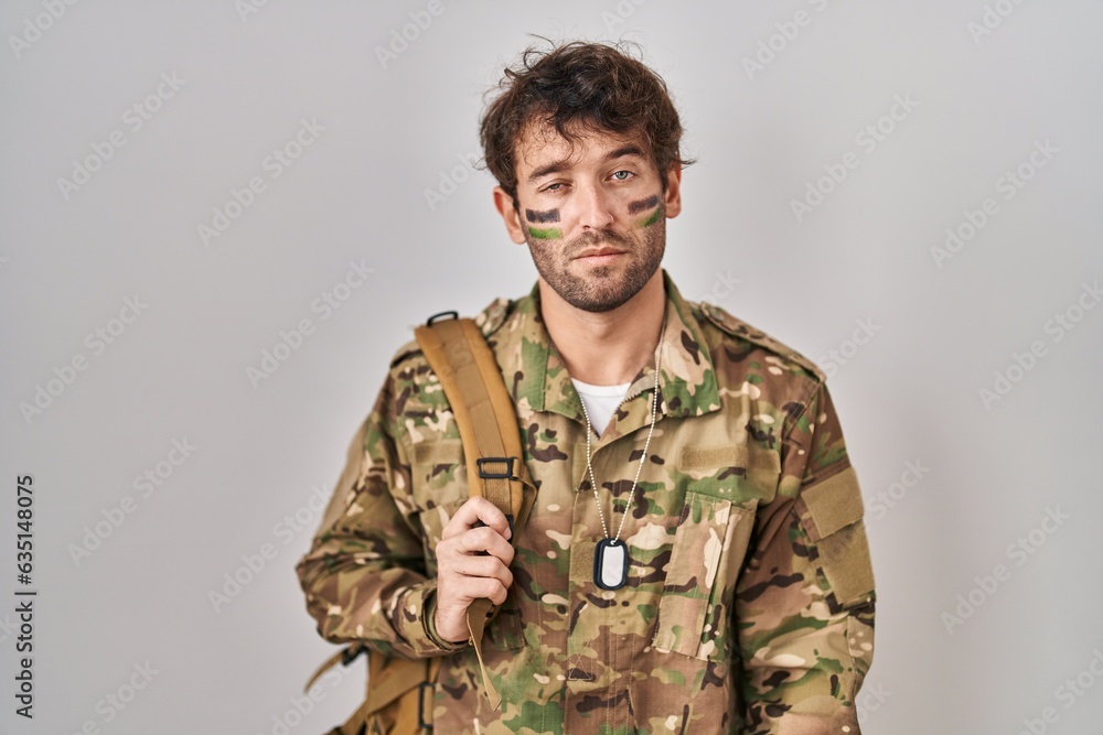 Hispanic young man wearing camouflage army uniform looking sleepy and tired, exhausted for fatigue and hangover, lazy eyes in the morning. Hispanic young man wearing camouflage army uniform looking sleepy and tired, exhausted for fatigue and hangover, lazy eyes in the morning.