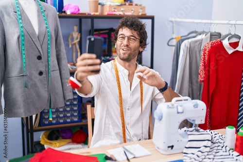 Young hispanic man tailor smiling confident having video call at clothing factory