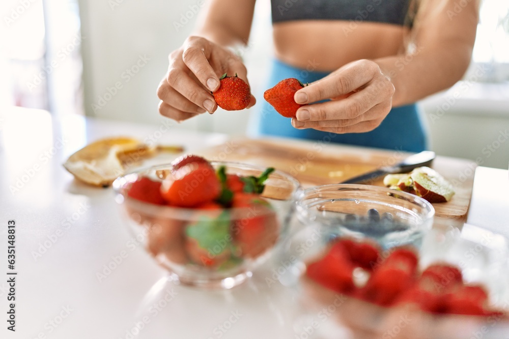 Young woman hoding strawberries at kitchen Young woman hoding strawberries at kitchen