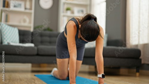 Young beautiful hispanic woman stretching back sitting on floor at home
