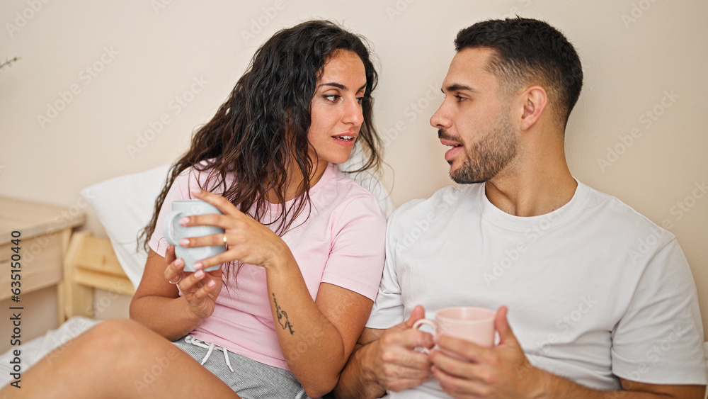 Man and woman couple sitting on bed drinking coffee at bedroom Man and woman couple sitting on bed drinking coffee at bedroom