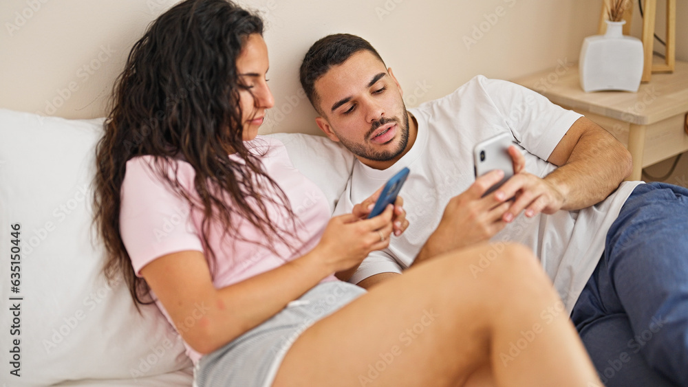 Obraz premium Man and woman couple lying on bed using smartphones at bedroom
