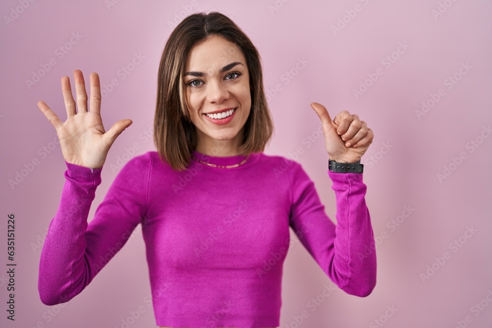 Hispanic woman standing over pink background showing and pointing up with fingers number six while smiling confident and happy. Hispanic woman standing over pink background showing and pointing up with fingers number six while smiling confident and happy.