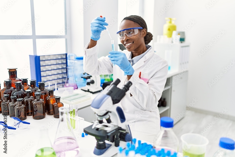 African american woman scientist pouring liquid on test tube at laboratory African american woman scientist pouring liquid on test tube at laboratory