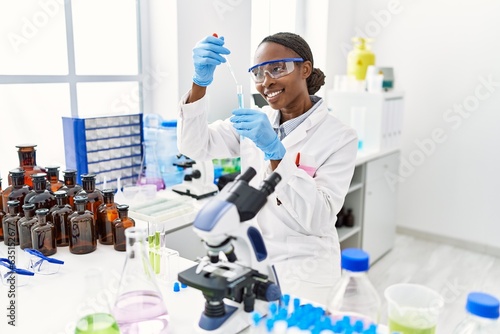 African american woman scientist pouring liquid on test tube at laboratory