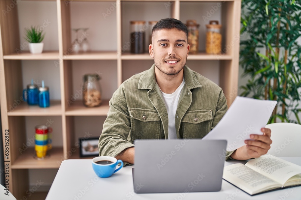 Young hispanic man sitting on table studying at home Young hispanic man sitting on table studying at home