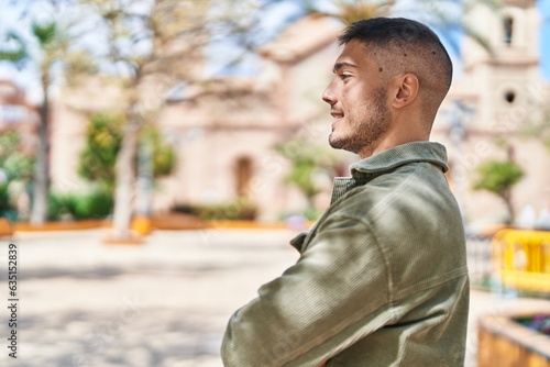 Young hispanic man smiling confident standing with arms crossed gesture at park