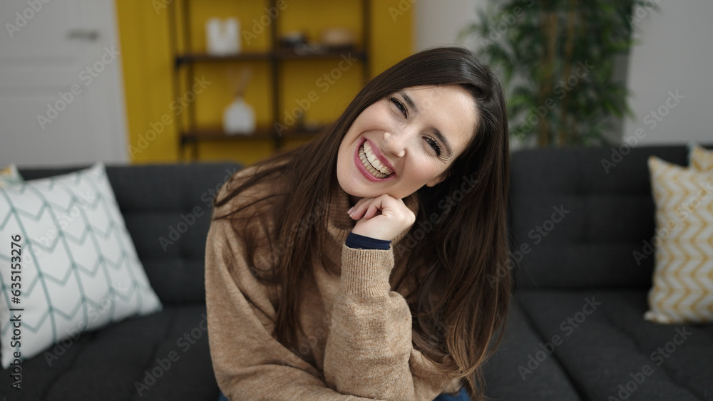 Fototapeta premium Beautiful hispanic woman smiling confident sitting on sofa at home