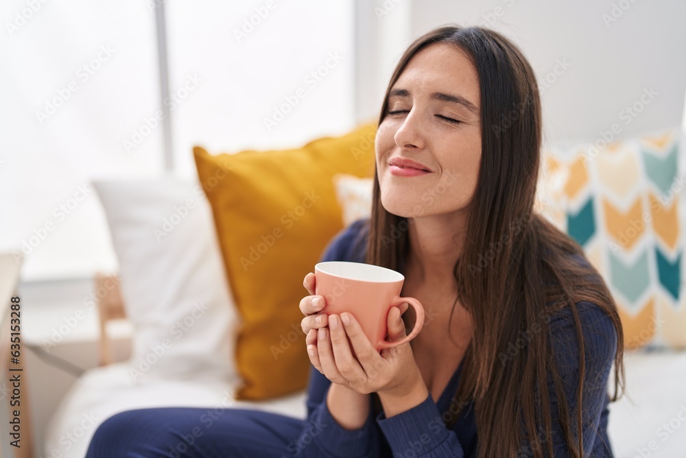 Young beautiful hispanic woman drinking cup of coffee sitting on bed at bedroom Young beautiful hispanic woman drinking cup of coffee sitting on bed at bedroom