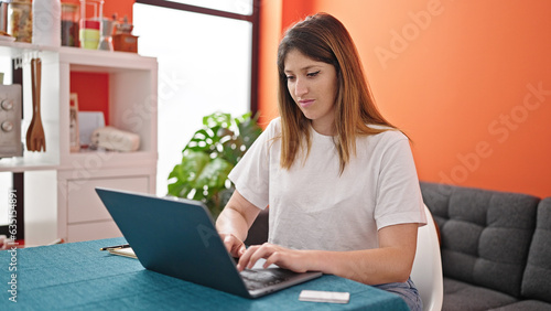 Young blonde woman using laptop at dinning room