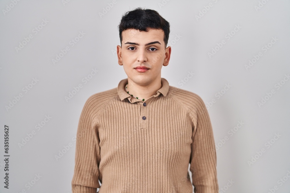 Obraz premium Non binary person standing over isolated background relaxed with serious expression on face. simple and natural looking at the camera.