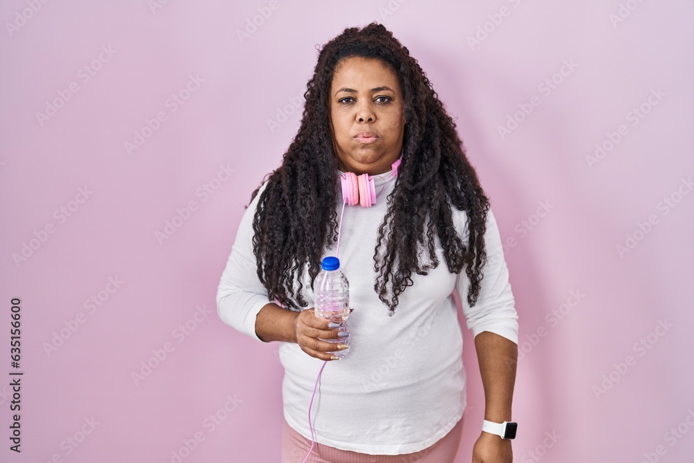 Plus size hispanic woman wearing sportswear and headphones looking sleepy and tired, exhausted for fatigue and hangover, lazy eyes in the morning. Plus size hispanic woman wearing sportswear and headphones looking sleepy and tired, exhausted for fatigue and hangover, lazy eyes in the morning.