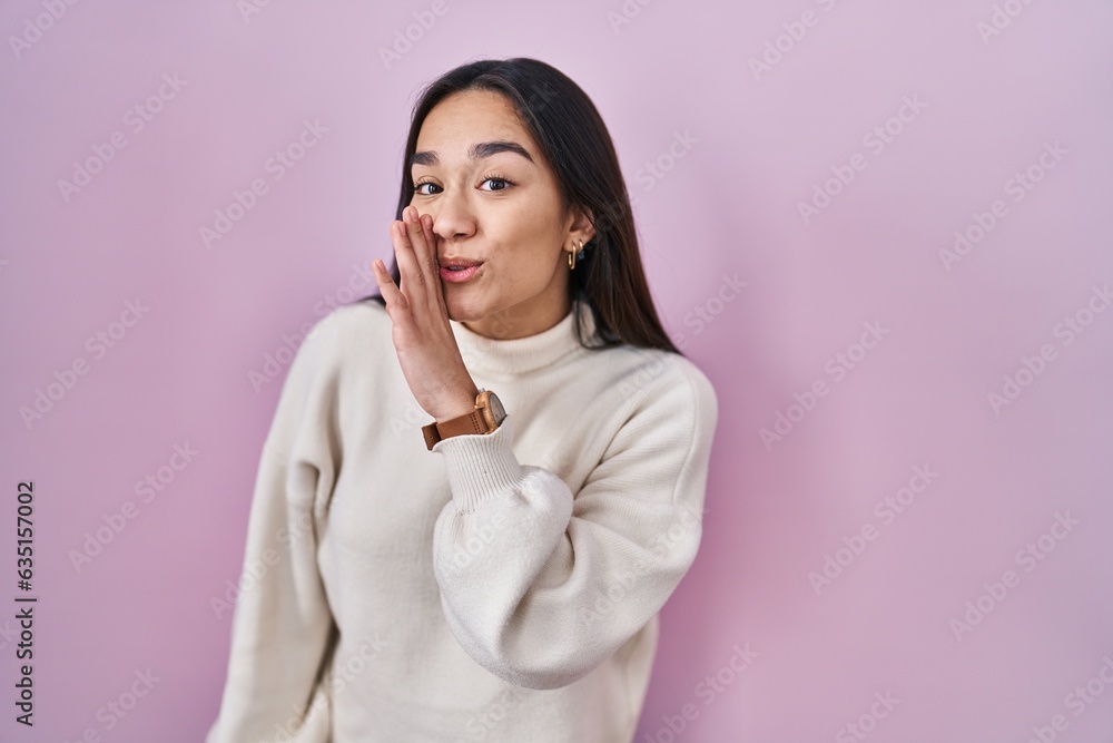 Young south asian woman standing over pink background hand on mouth telling secret rumor, whispering malicious talk conversation Young south asian woman standing over pink background hand on mouth telling secret rumor, whispering malicious talk conversation