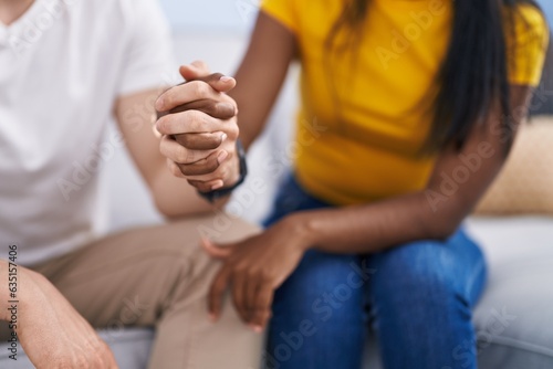Man and woman interracial couple with hands together at home