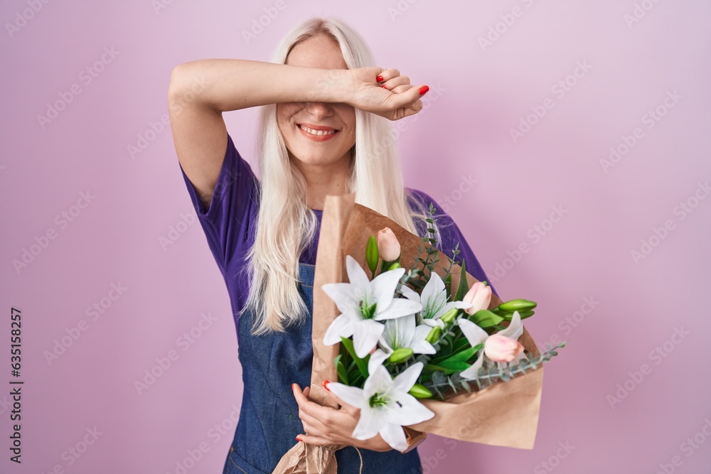 Caucasian woman holding bouquet of white flowers smiling cheerful playing peek a boo with hands showing face. surprised and exited