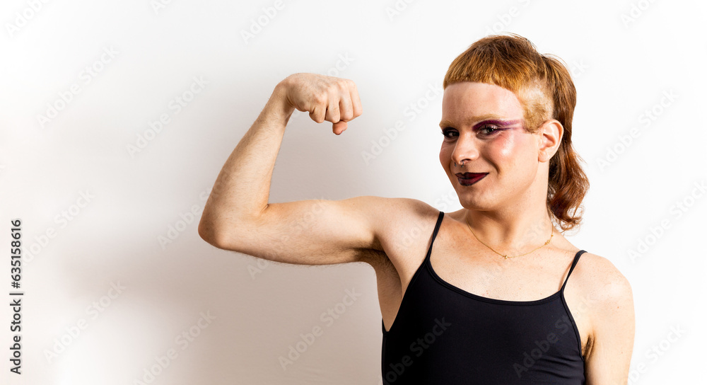 A red-haired non-binary person poses on a white background showing the biceps happily. Concept of support for the LGBTI collective, pride for the LGBT collective. Copy space for advertising. A red-haired non-binary person poses on a white background showing the biceps happily. Concept of support for the LGBTI collective, pride for the LGBT collective. Copy space for advertising.