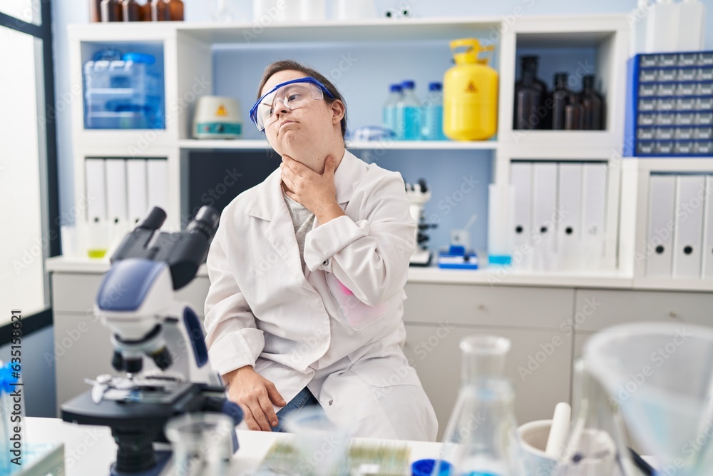 Hispanic girl with down syndrome working at scientist laboratory touching painful neck, sore throat for flu, clod and infection Hispanic girl with down syndrome working at scientist laboratory touching painful neck, sore throat for flu, clod and infection