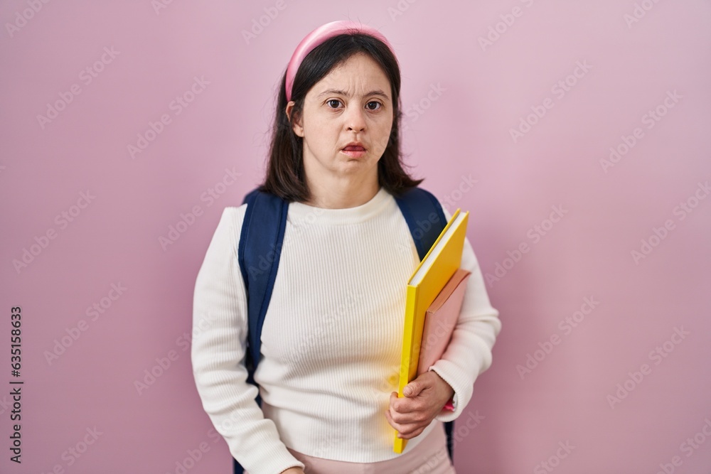 Woman with down syndrome wearing student backpack and holding books looking sleepy and tired, exhausted for fatigue and hangover, lazy eyes in the morning. Woman with down syndrome wearing student backpack and holding books looking sleepy and tired, exhausted for fatigue and hangover, lazy eyes in the morning.