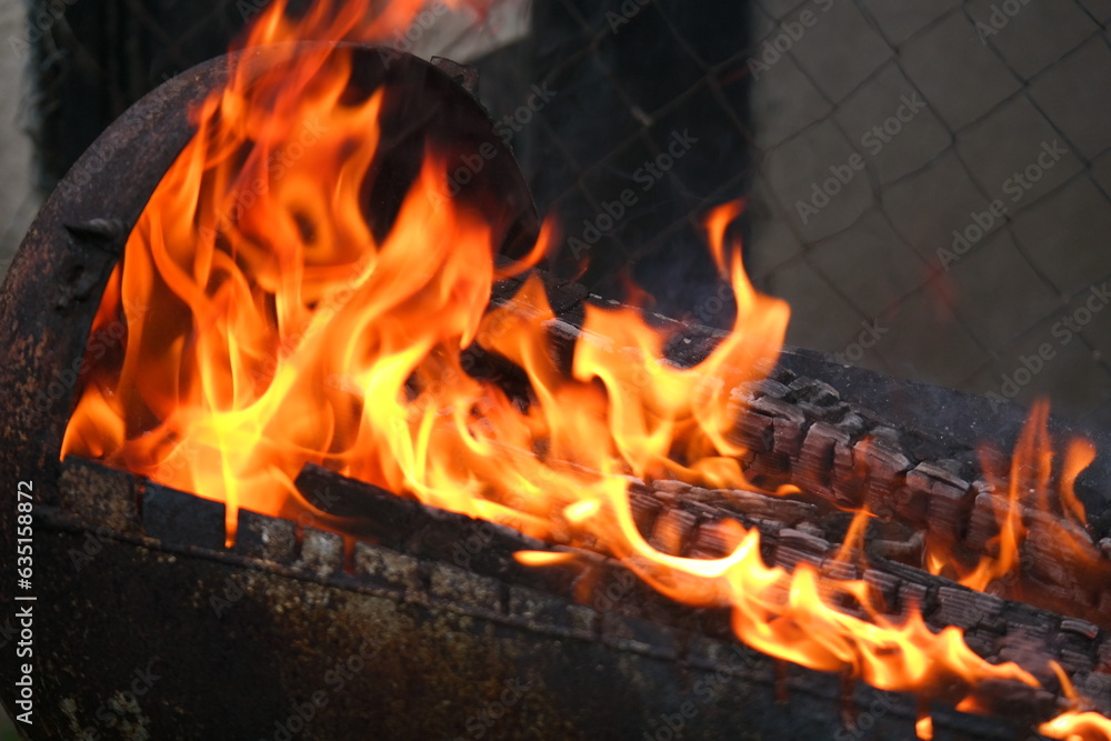 Naklejka premium burning wood and paper. firewood is burning. tongues of flame. orange flame. bonfire. wood-fired cooking. firewood is burning for cooking barbecue