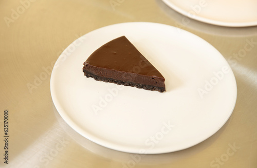 A piece of chocolate cake in white dish on the stainless table background