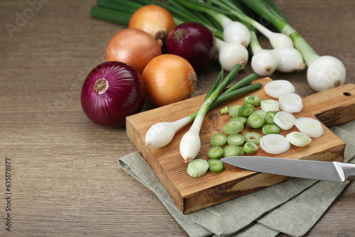 Different kinds of onions on wooden table, closeup. Space for text