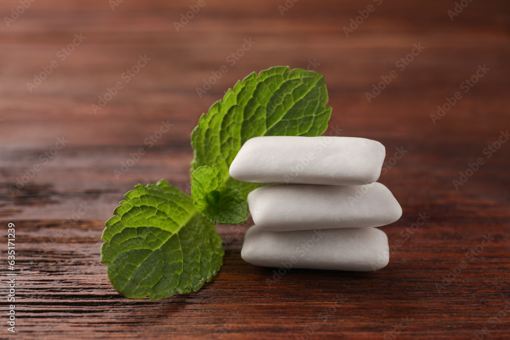 Tasty white chewing gums and mint leaves on wooden table, closeup Tasty white chewing gums and mint leaves on wooden table, closeup