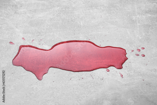 Puddle of red liquid on light grey surface