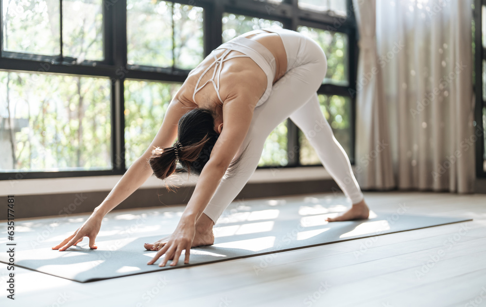 Naklejka premium Female happiness Attractive young asian woman doing yoga stretching exercise on mat yoga & fitness exercises. Healthy lifestyle Calmness and relax at home.