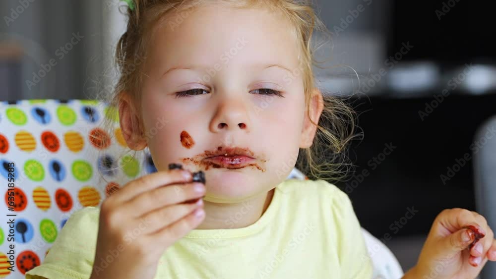 Little girl with blond hair eating homemade chocolate with dirty mouth and hands in home kitchen Little girl with blond hair eating homemade chocolate with dirty mouth and hands in home kitchen