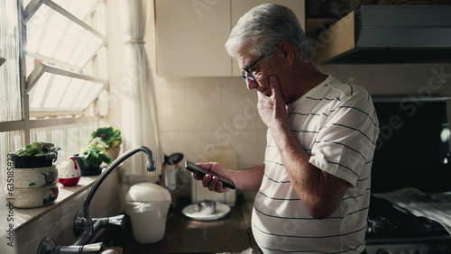 Fotografi Pensive senior man looking at phone screen pondering dilemma and decision-making