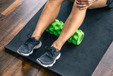 Sport woman using foam roller for muscle and fascia stretching foot.