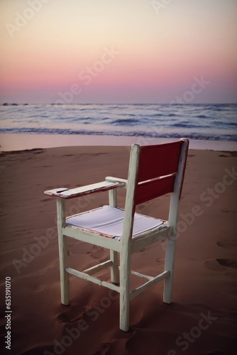 A Red And White Chair Sitting On Top Of A Sandy Beach