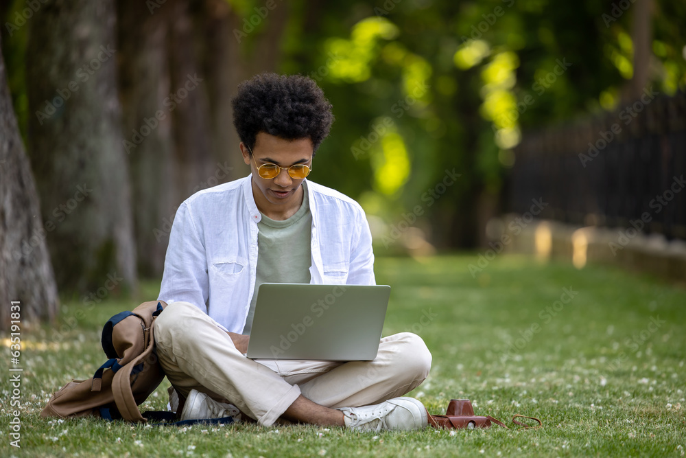 Young curly-haired man working on laptop in the park Young curly-haired man working on laptop in the park
