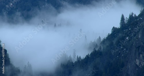 Clouds move quickly around trees as storm clears along Merced River canyon