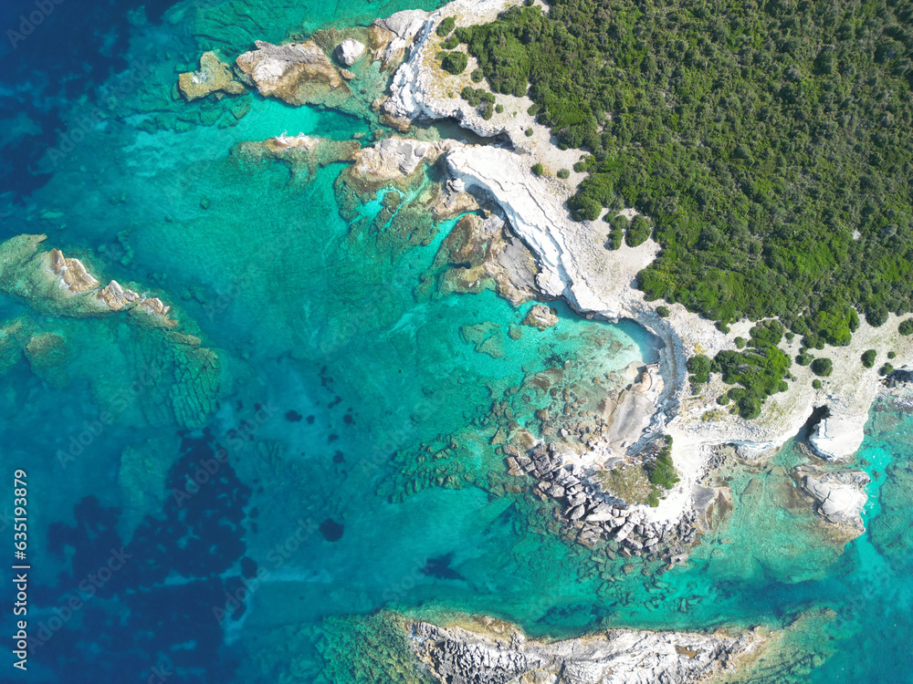 Captured from the sky, a drone showcases Greece's azure waters kissing sun-kissed shores, framing an idyllic Mediterranean mosaic.