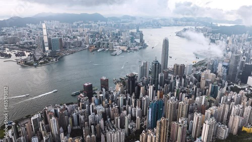 Above cloud cityscape view of Hong Kong island, drone aerial hyperlapse time lapse. Skyscraper buildings in financial district, ship transportation on Victoria harbour. Asia tourism travel concept photo