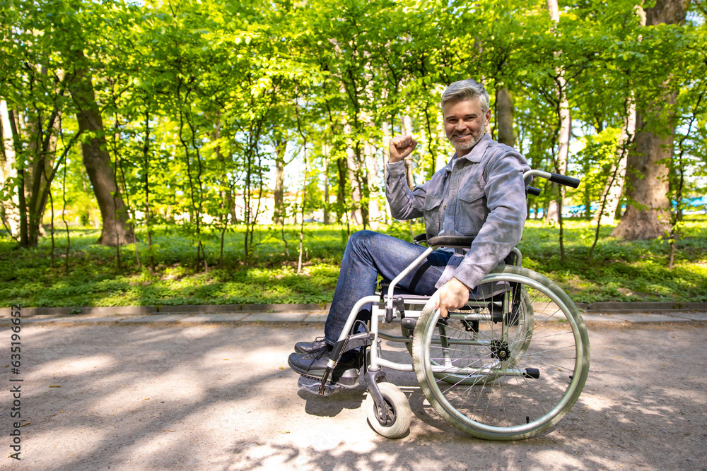 Gray haired disable man in wheelchair spending free time in park. Gray haired disable man in wheelchair spending free time in park.
