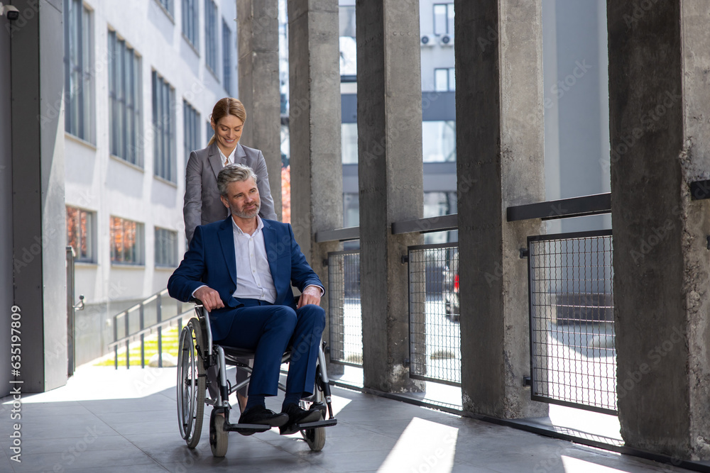 Woman assisting man business partner in wheelchair going to office.