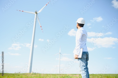 Indian Engineer in wheat field checking on turbine production