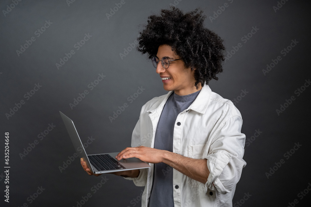 Young freelance with a laptop on grey background Young freelance with a laptop on grey background