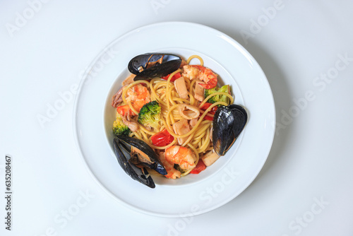 spaghetti pasta with seafood and cherry tomatoes on a white plate on a pure white table