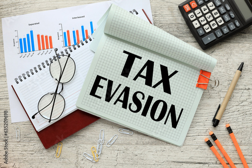 notepad with a spring on the work table. financial charting calculator. words tax evasion