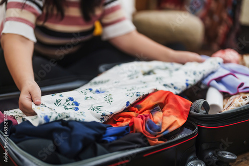 Woman packing suitcase at home preparing to summer travel trip .