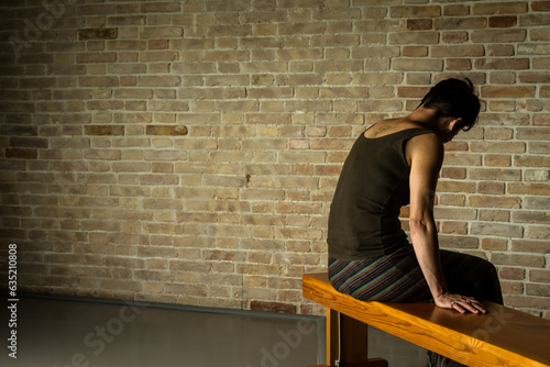 Una donna sola e triste seduta su una panchina di fronte a un muro photo