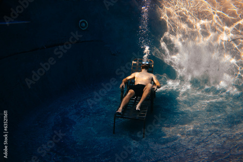 Man at bottom of pool, swimmer on pool chair