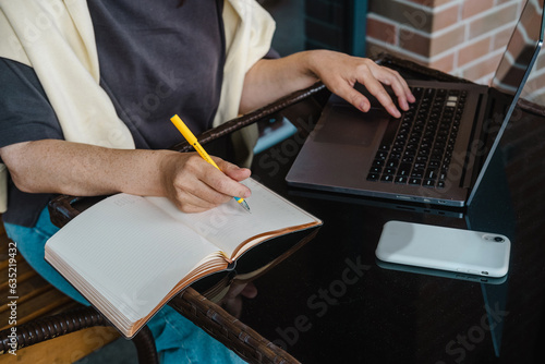 Woman working online in cafe outdoor writng in planner close up photo