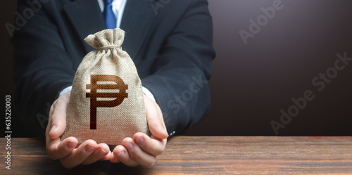Businessman holds out philippine peso money bag. Getting a grant. Mortgage, loan approval. Easy Money. Salary benefits. Attracting investments. Deposit savings. Cashback. Banking and crediting.